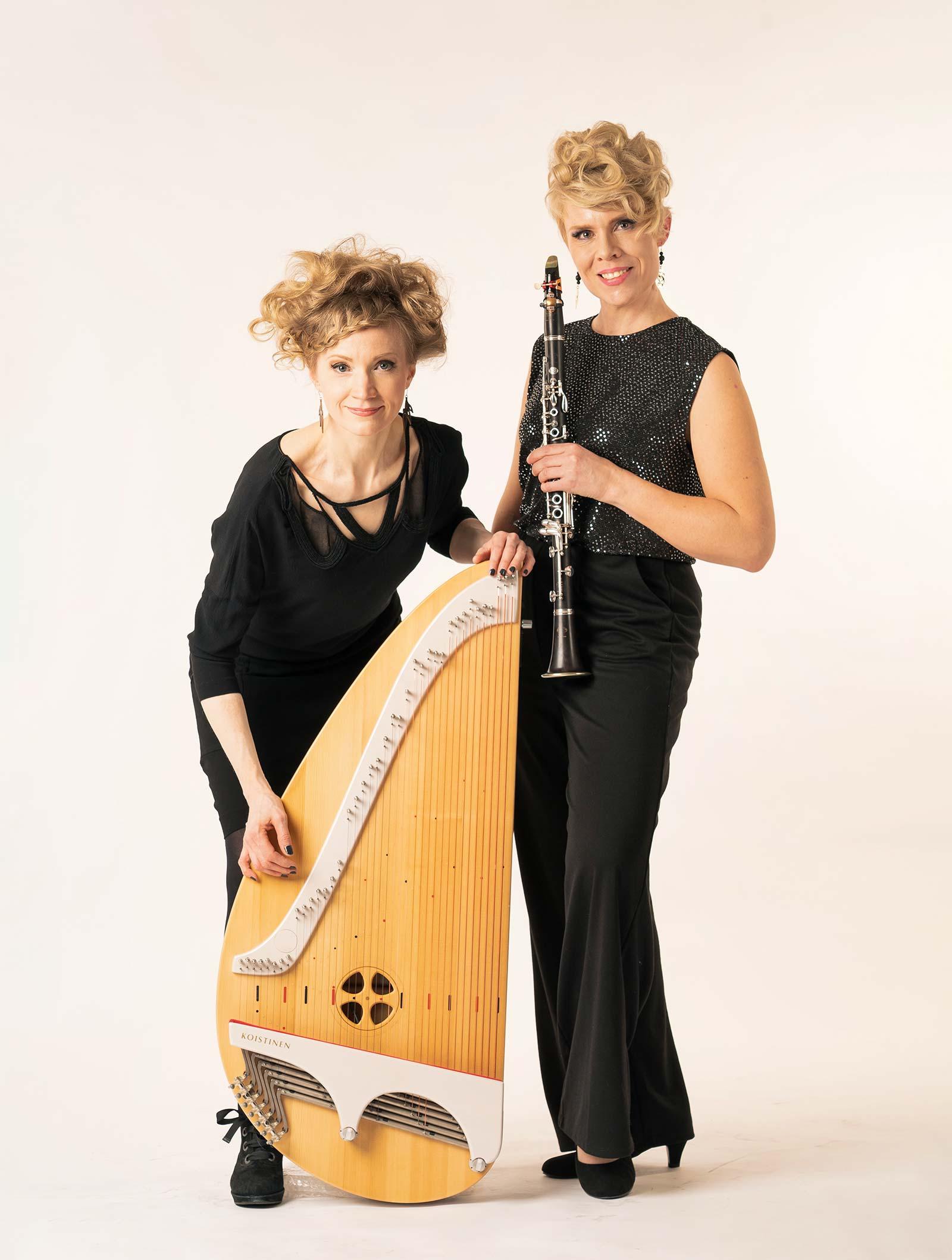 Eva Alkula vasemmalla kanteleen kanssa ja vieressä Reetta Näätänen klarinetin kanssa. Kokovartalokuva vaalealla taustalla.
