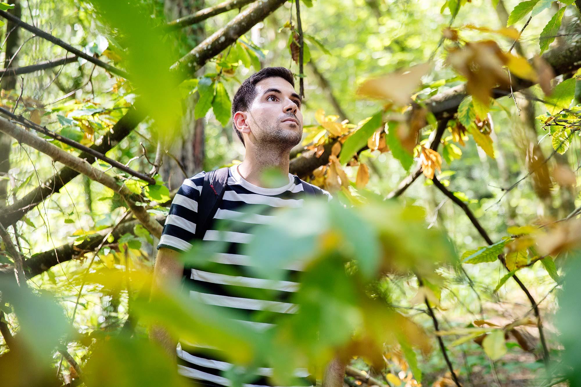 Mikel Urquiza metsän keskellä katse ylöspäin suunnattuna. Ympärillä paljon vihreitä puiden oksia.